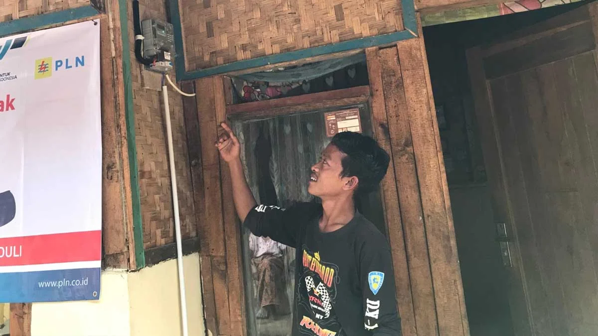 warga setiawargi menunjukkan kWh listrik yang baru dipasang PLN di rumahnya